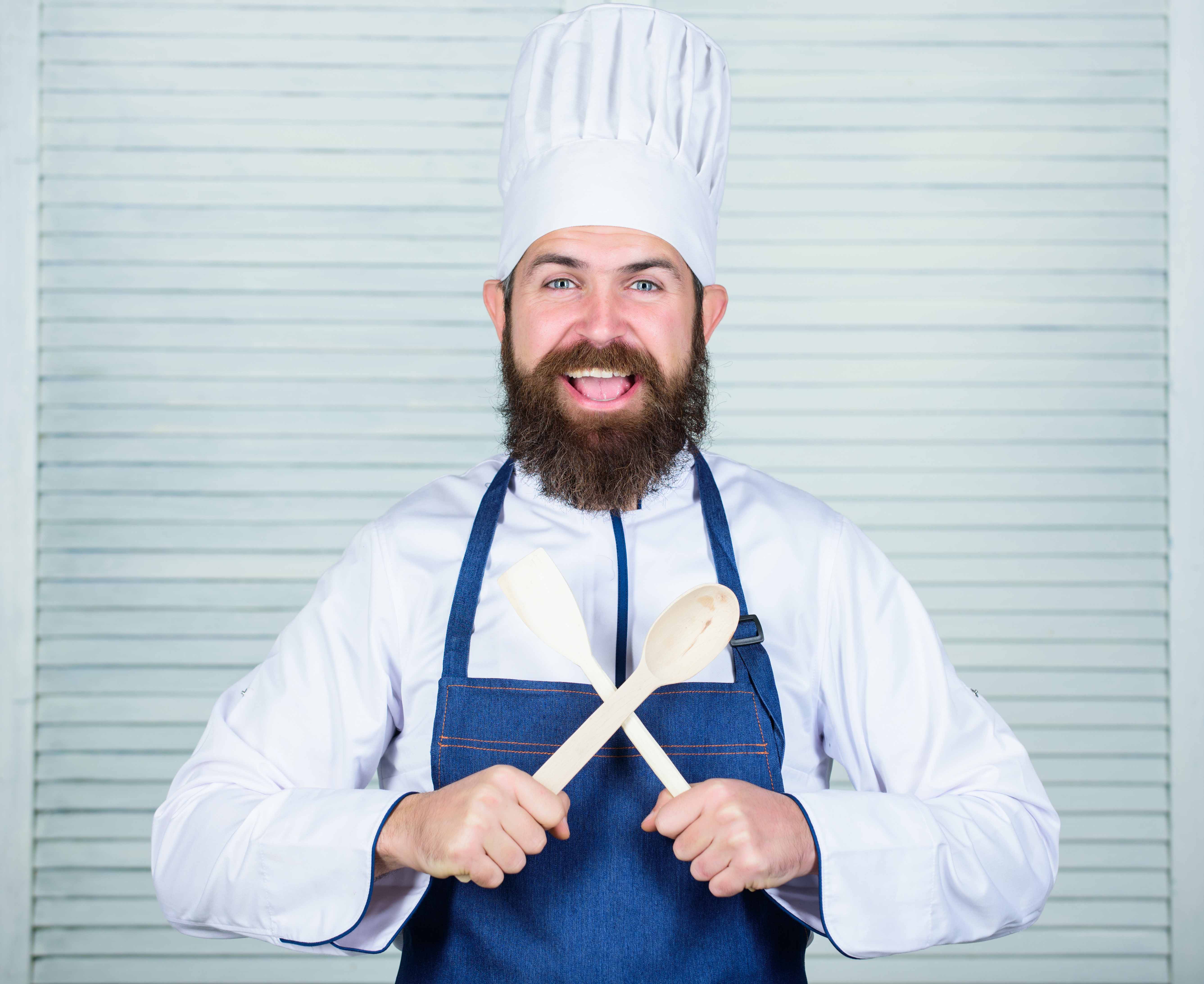 Hipster bearded chef hold wooden spoon. Kitchenware and cooking